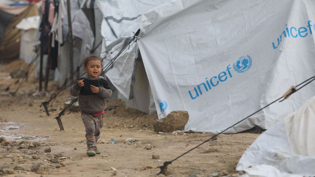 A Palestinian child walks among storm-damaged tents provided by UNICEF in Gaza