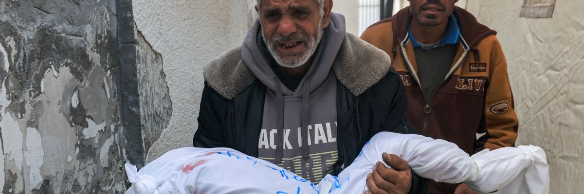 A Palestinian from Khan Yunis follows his father, who is carrying the wrapped body of his daughter