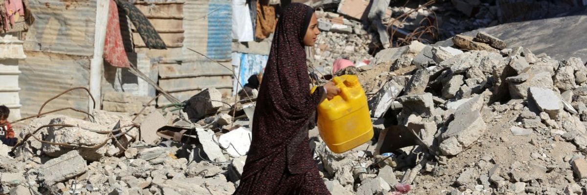 A Palestinian girl carries a  jerry can amid the ruins of Khan Yunis, Gaza