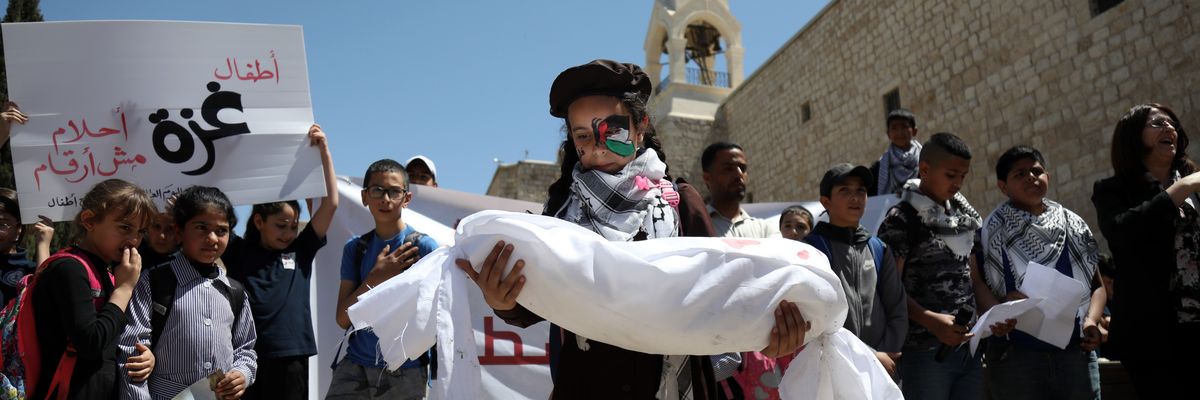 A Palestinian girl carries the representative shroud of a child