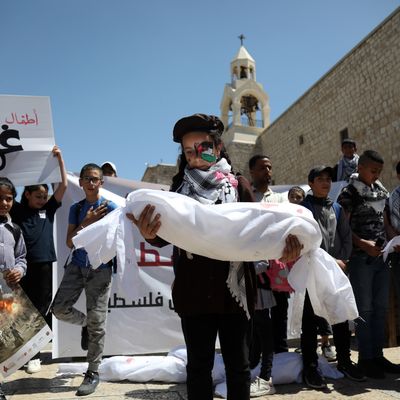 A Palestinian girl carries the representative shroud of a child