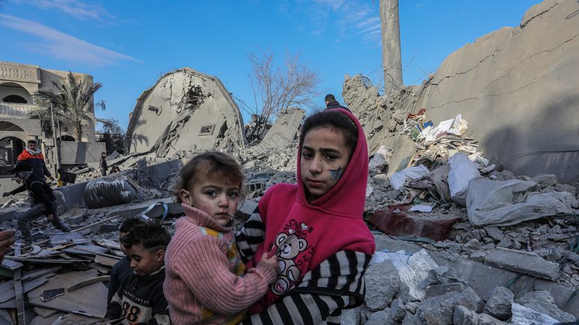  A Palestinian girl holds a child on rubble 