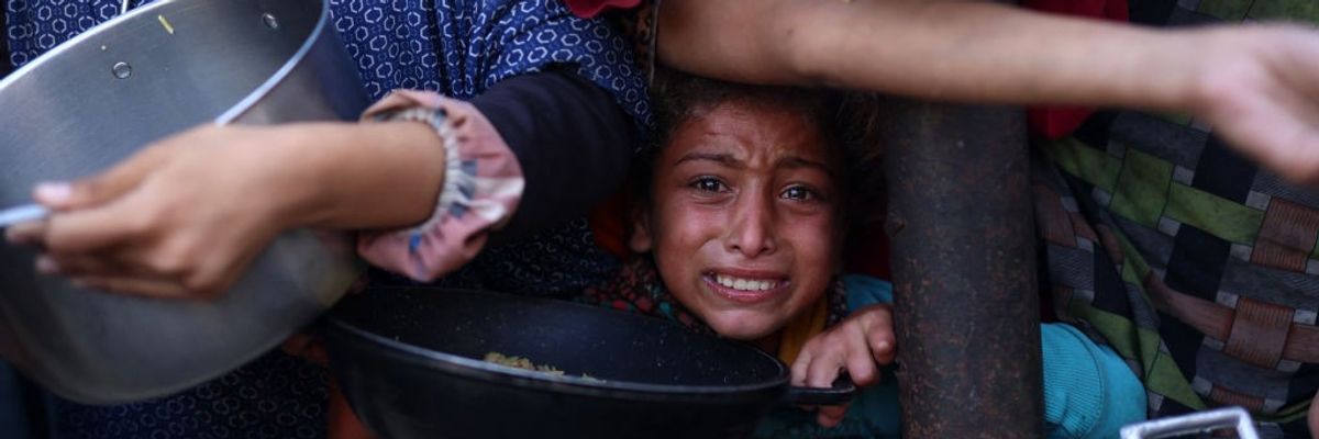 A Palestinian girl waits in a queue to receive food