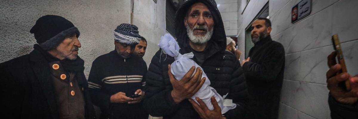 A Palestinian man carried the shrouded body of an infant who died of exposure in Gaza