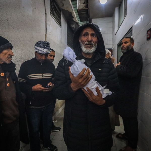 A Palestinian man carried the shrouded body of an infant who died of exposure in Gaza