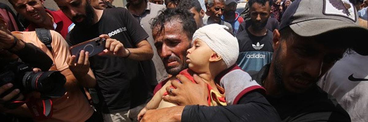 A Palestinian man carries a child to receive medical treatment