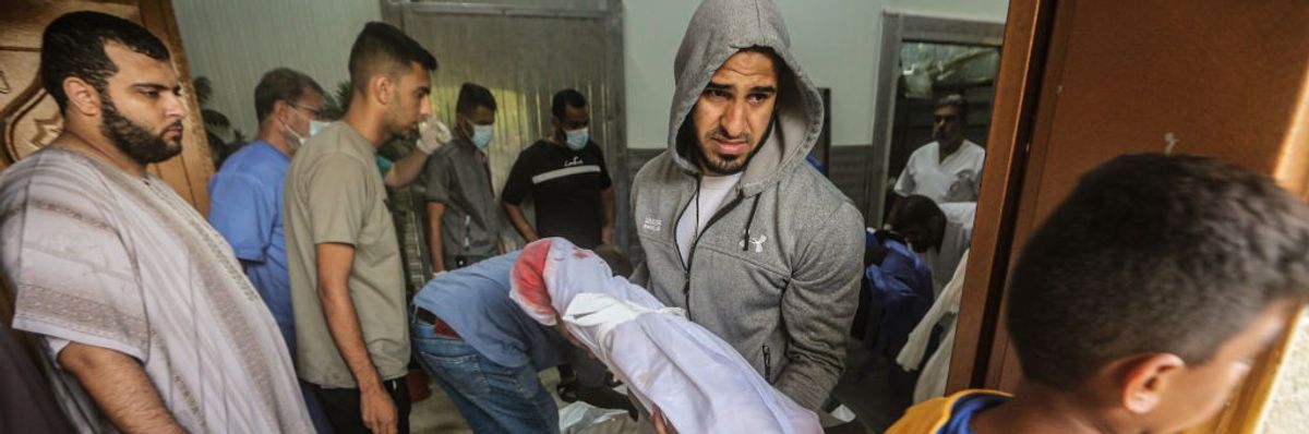 A Palestinian man carries a dead child in Khan Younis