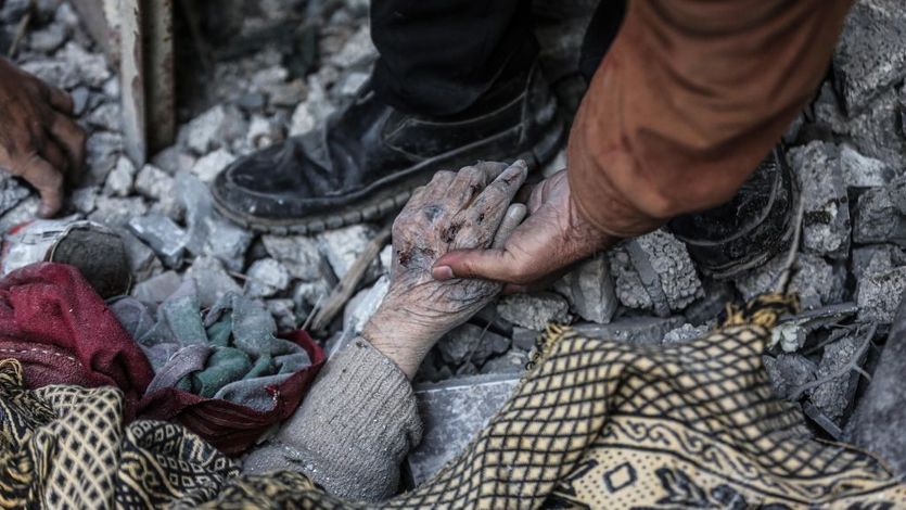 A Palestinian man holds the hand of a dead relative