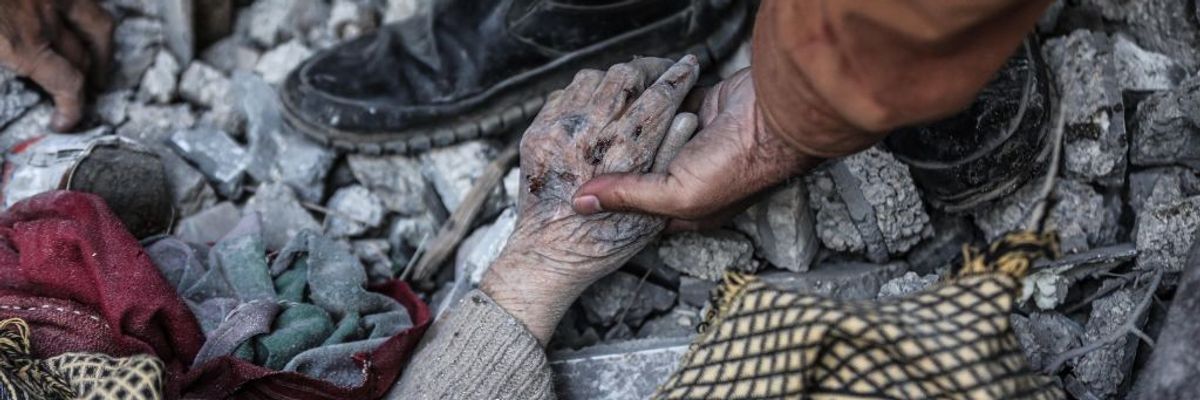 A Palestinian man holds the hand of a dead relative