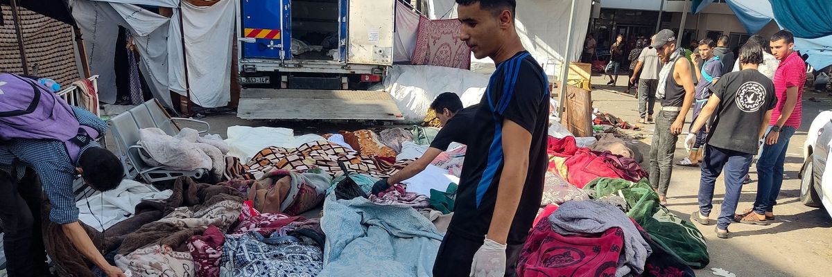 A Palestinian man looks at bodies covered in blankets after the al-Buraq School in Gaza was bombed.