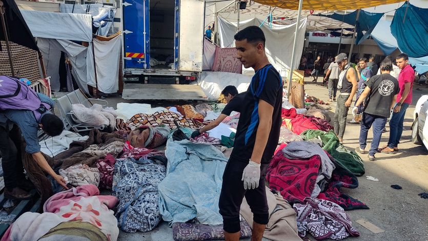 A Palestinian man looks at bodies covered in blankets after the al-Buraq School in Gaza was bombed.