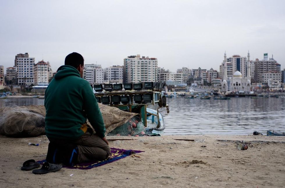 A Palestinian man prays at Gaza's port, where the enclave's crucial fishing industry now struggles. Photo by Kaamil Ahmed/Mongabay.