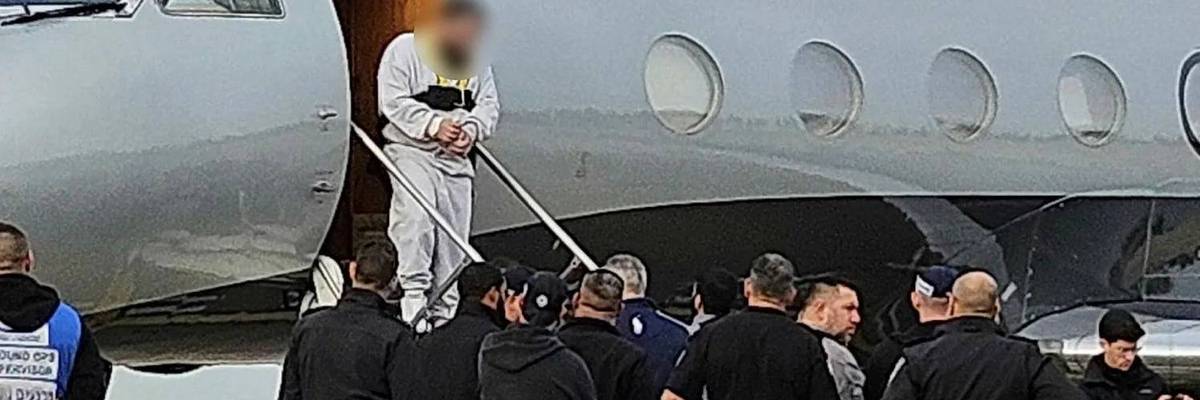 A Palestinian man with his hands bound steps off the private jet