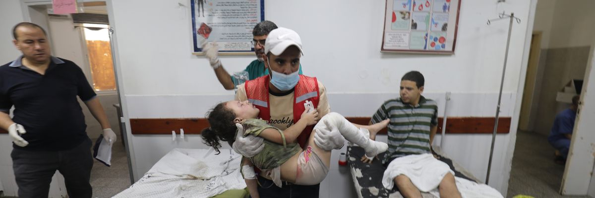 A Palestinian medic carries a wounded girl in a Gaza hospital