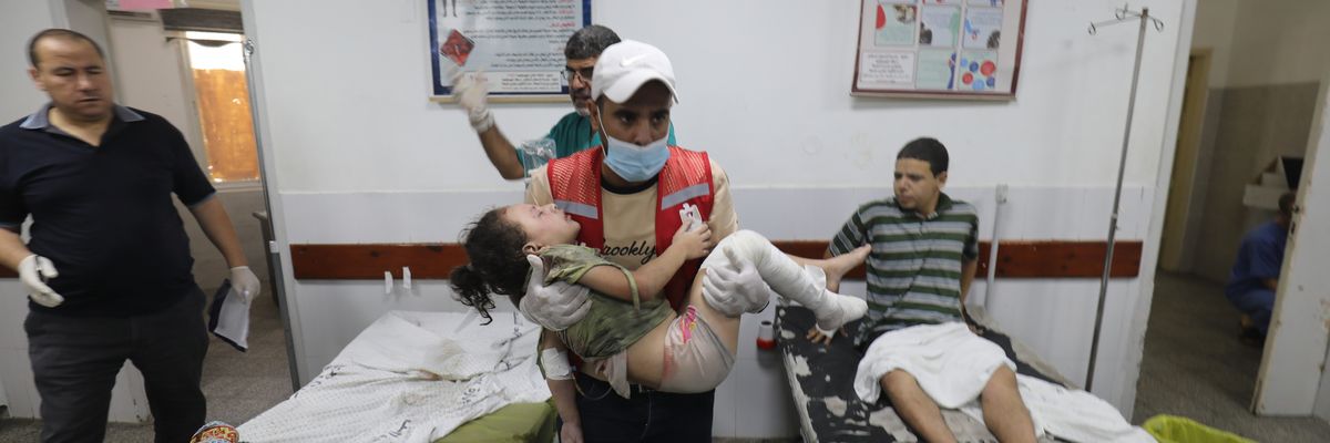 A Palestinian medic carries a wounded girl in a Gaza hospital