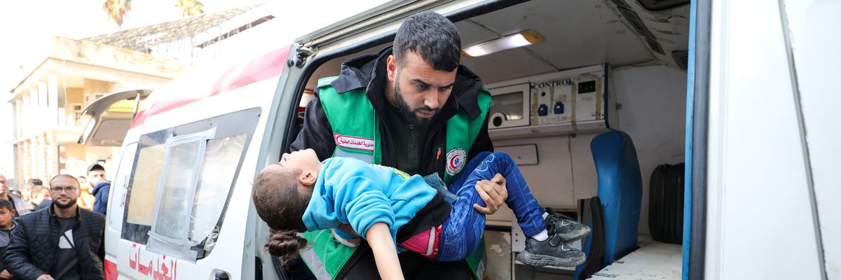 A Palestinian medic carries an injured child