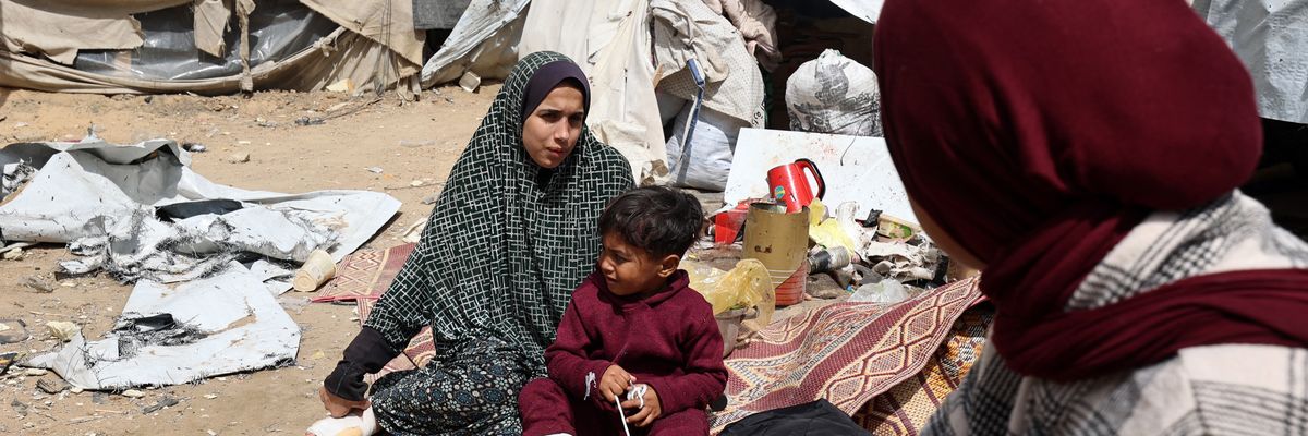 A Palestinian woman and child sit with injuries by a tent.