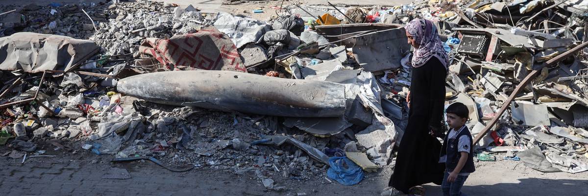A Palestinian woman and child walk by an unexploded Israeli munition in Gaza City