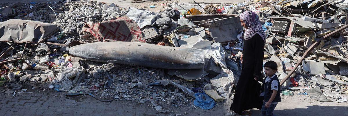 A Palestinian woman and child walk by an unexploded Israeli munition in Gaza City