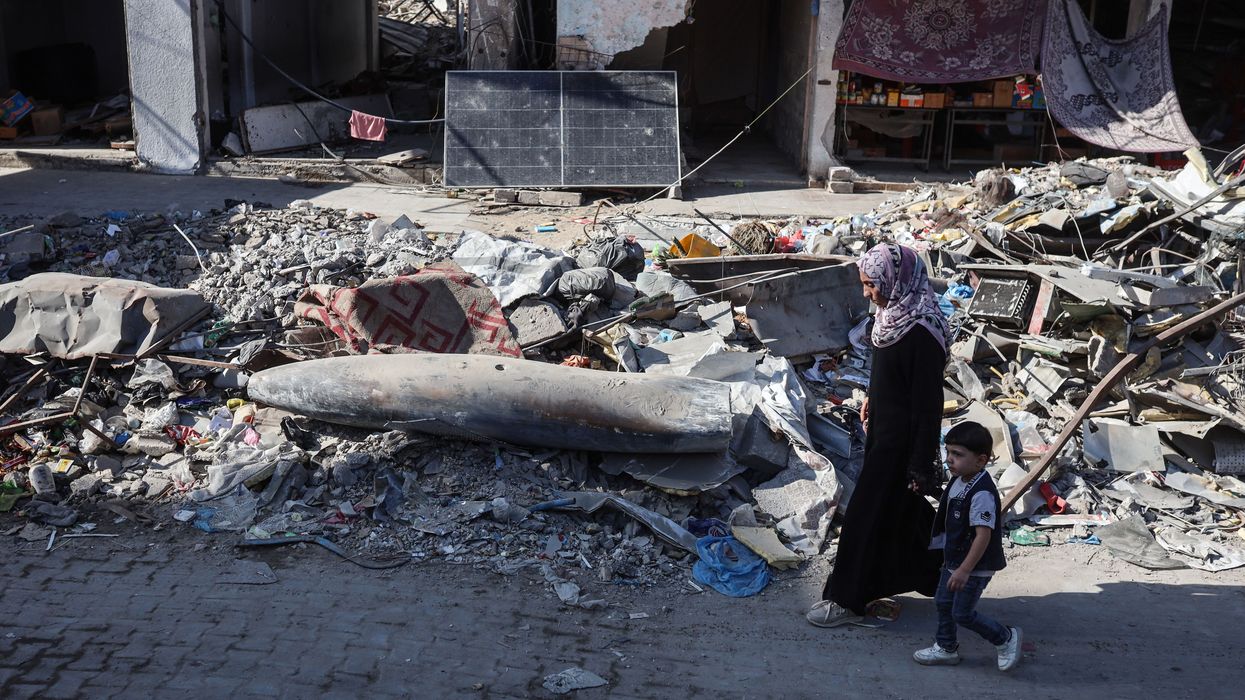 A Palestinian woman and child walk by an unexploded Israeli munition in Gaza City