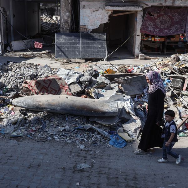 A Palestinian woman and child walk by an unexploded Israeli munition in Gaza City
