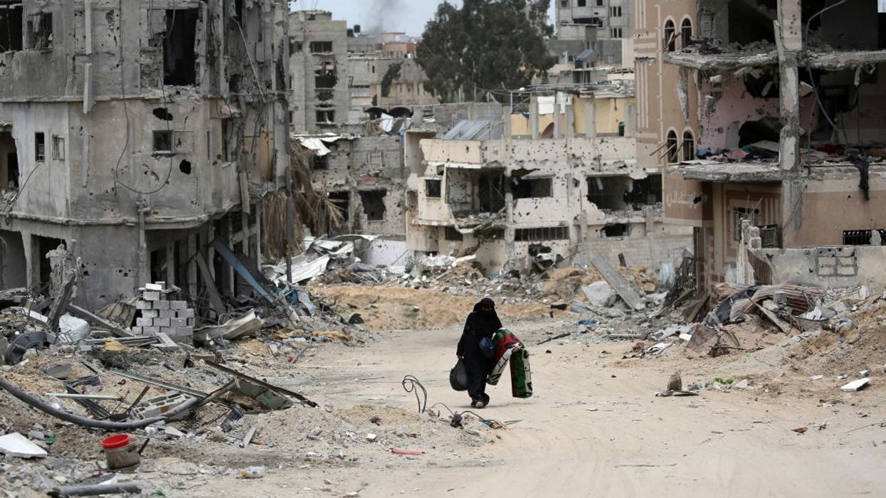 A Palestinian woman carries belongings through bombed-out Gaza