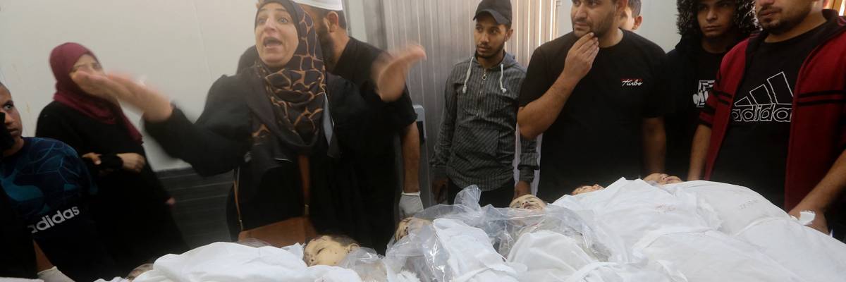 A Palestinian woman is distraught as she stands near the bodies of numerous children killed in Israeli attacks.