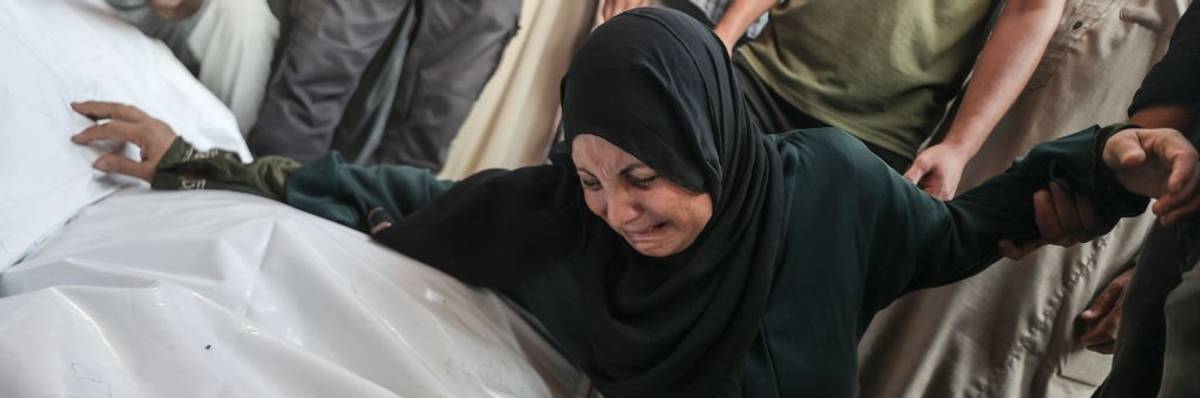 A Palestinian woman mourns over plastic bags containing bodies of Gazans killed in an Israeli airstrike