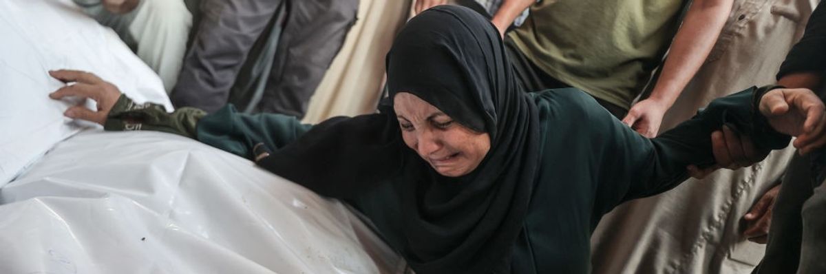 A Palestinian woman mourns over plastic bags containing bodies of Gazans killed in an Israeli airstrike