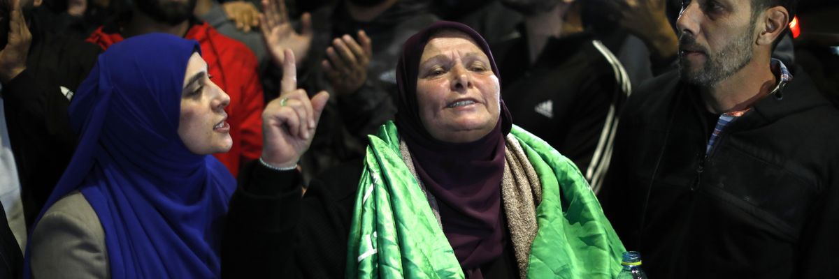 A Palestinian woman points to the sky in celebration and relief as prisoners are released. 