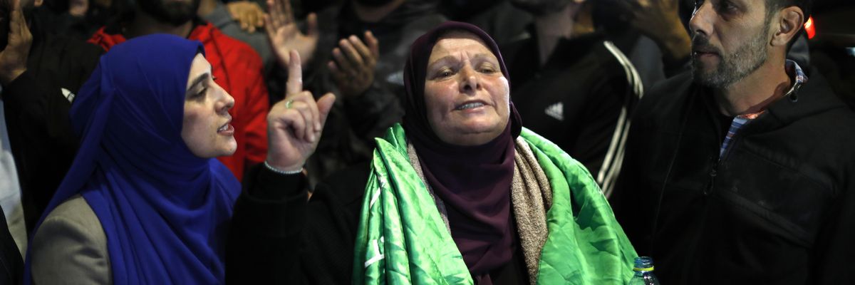 A Palestinian woman points to the sky in celebration and relief as prisoners are released.