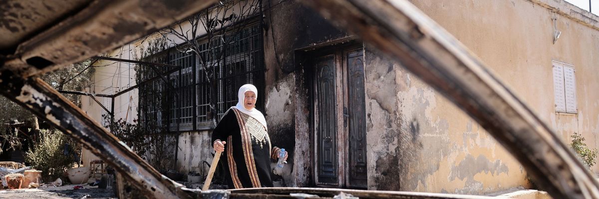 A Palestinian woman walks in Turmus Ayya after Israeli settlers attack.