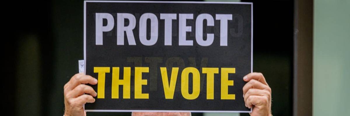 A participant holding a Protect The Vote sign outside NBC