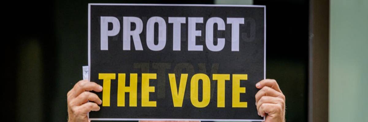A participant holding a Protect The Vote sign outside NBC