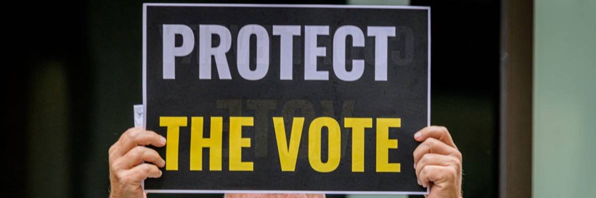 A participant holding a Protect The Vote sign outside NBC