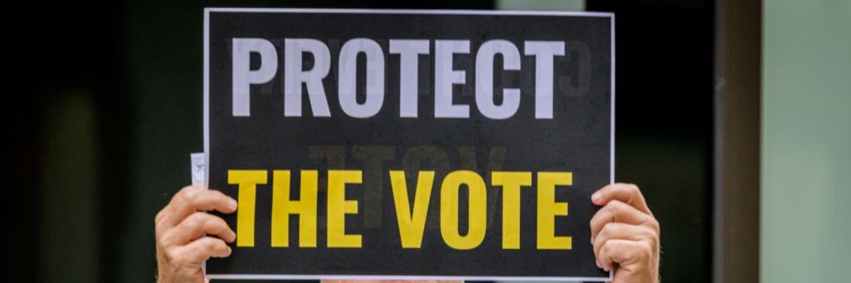 A participant holding a Protect The Vote sign outside NBC