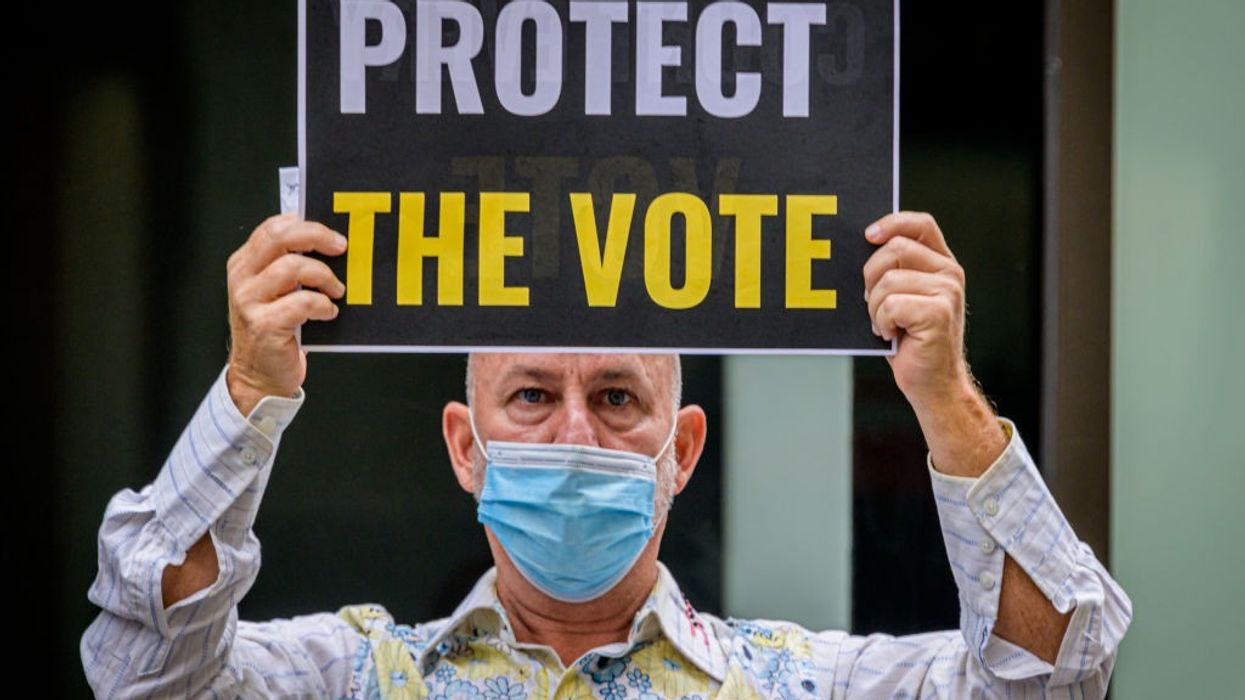 A participant holding a Protect The Vote sign outside NBC