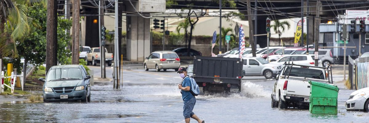 A pedestrian walks across a flooded street in Honolulu, Hawaii on December 7, 2021, the morning after a powerful winter tropical storm known as a Kona Low hit the Hawaii islands with heavy rain and high winds causing widespread flooding and power outages across the state.