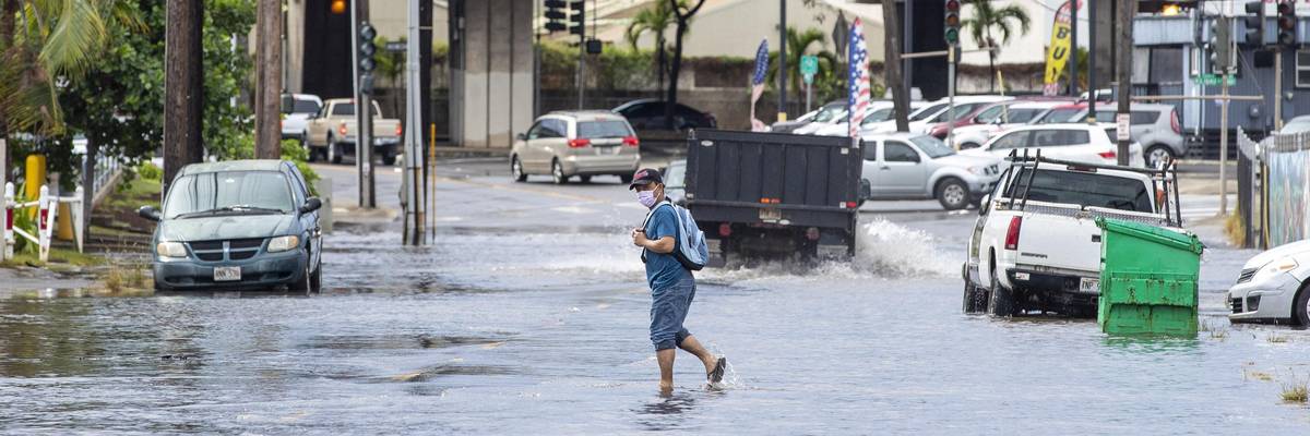 A pedestrian walks across a flooded street in Honolulu, Hawaii on December 7, 2021, the morning after powerful winter tropical storm known as a Kona Low hit the Hawaii islands with heavy rain and high winds causing wide spread flooding and power outages across the state. (Photo: Eugene Tanner/AFP via Getty Images)