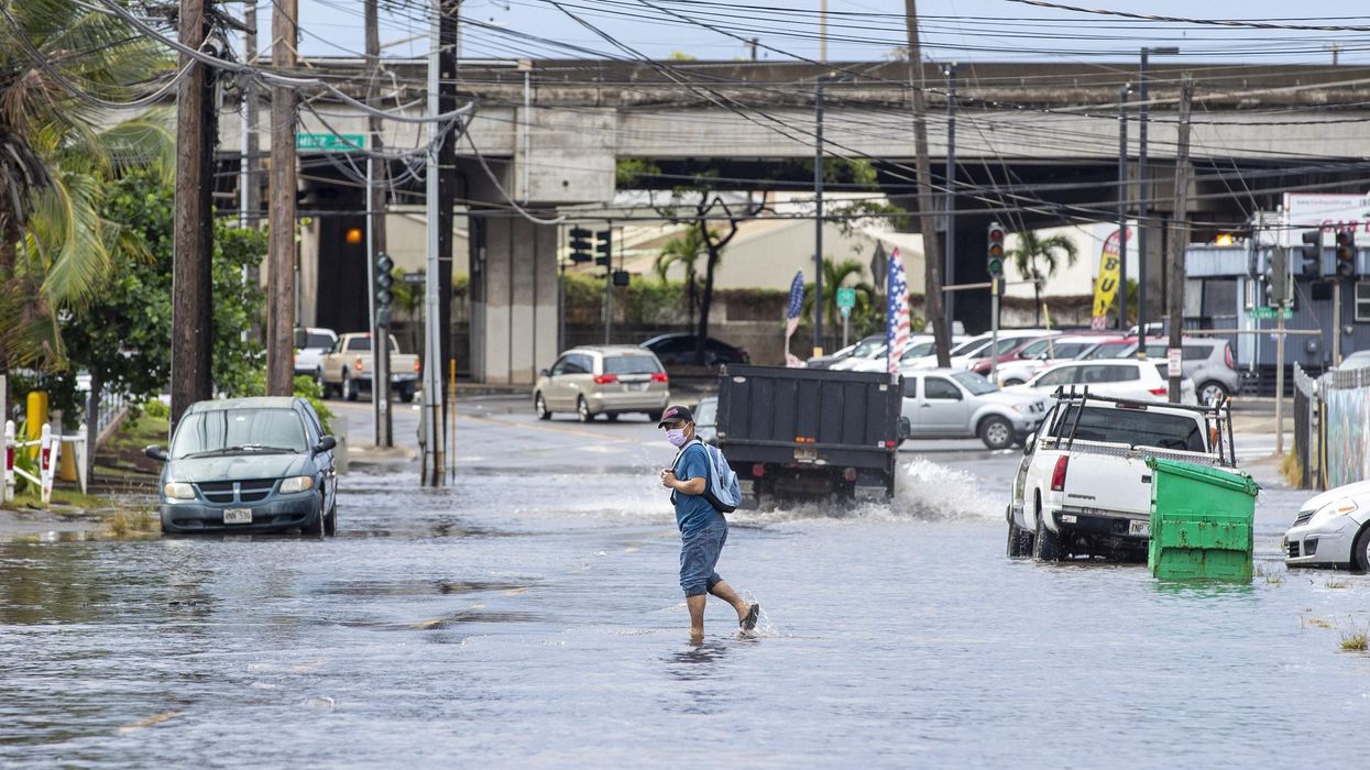 A pedestrian walks across a flooded street in Honolulu, Hawaii on December 7, 2021, the morning after powerful winter tropical storm known as a Kona Low hit the Hawaii islands with heavy rain and high winds causing wide spread flooding and power outages across the state. (Photo: Eugene Tanner/AFP via Getty Images)
