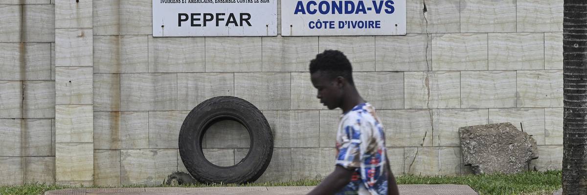 A pedestrian walks past a PEPFAR sign in Abidjan, Côte d'Ivoire