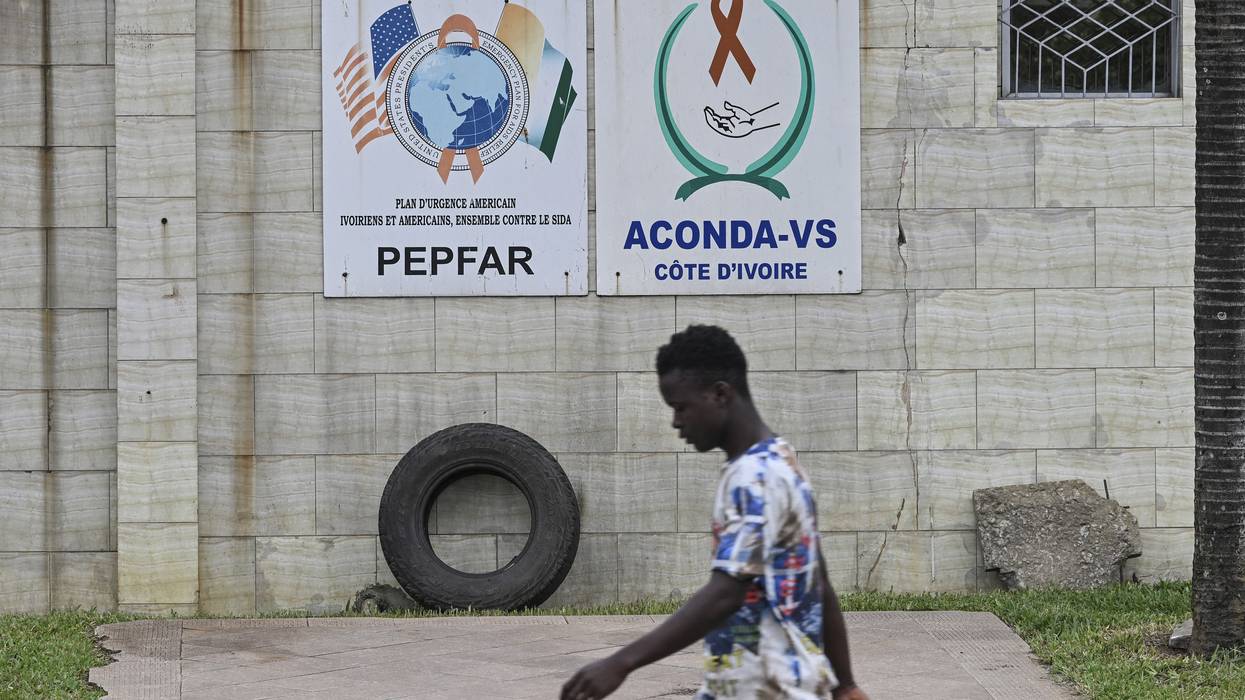 A pedestrian walks past a PEPFAR sign in Abidjan, Côte d'Ivoire