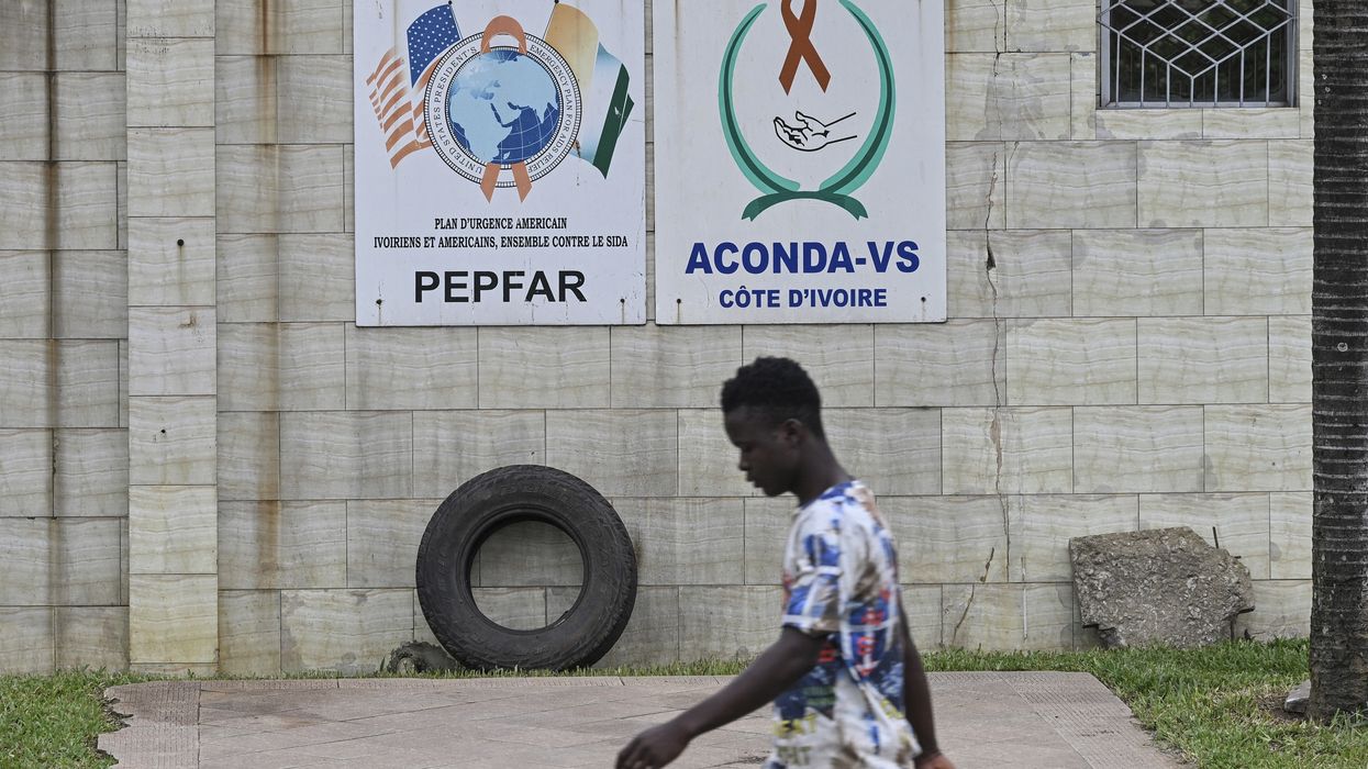 A pedestrian walks past a PEPFAR sign in Abidjan, Côte d'Ivoire