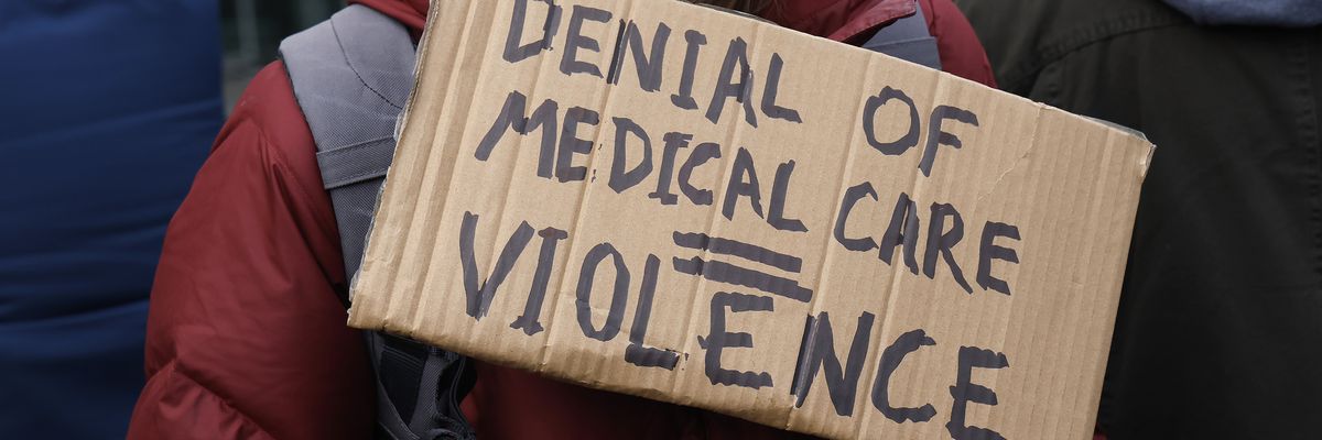 A person demonstrating against the healthcare industry holds a sign