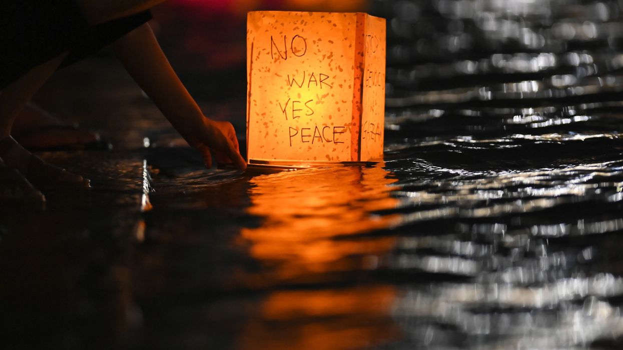 A person floats a lantern in Hiroshima reading, "No war, yes peace."
