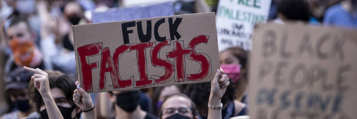 A person holds a "fuck fascists" sign at a protest.