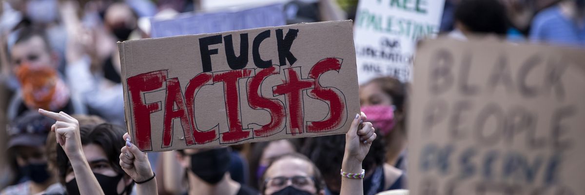 A person holds a "fuck fascists" sign at a protest.