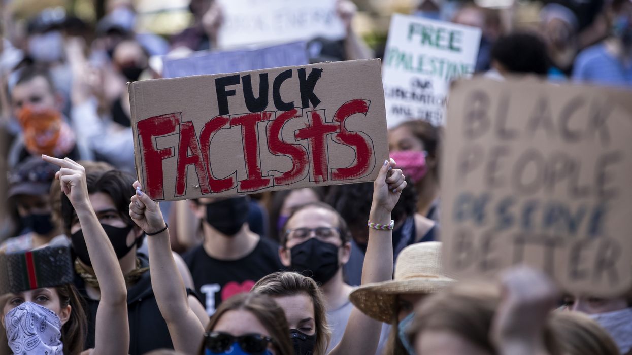 A person holds a "fuck fascists" sign at a protest.