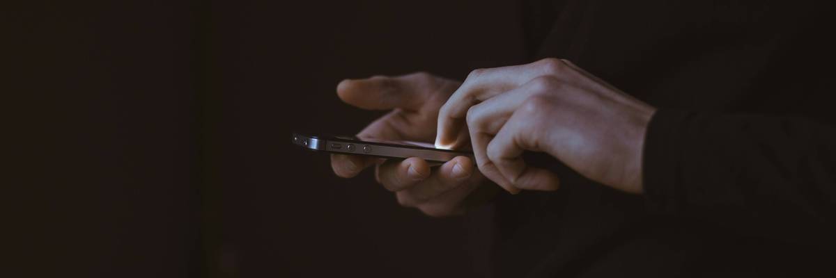 A person holds a phone against a black background.