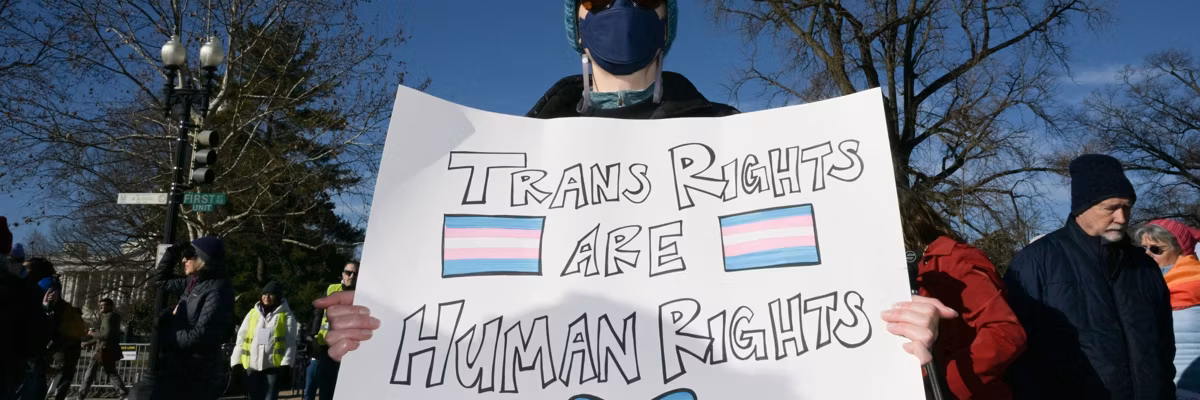 A person holds a poster saying, "Trans rights are human rights."